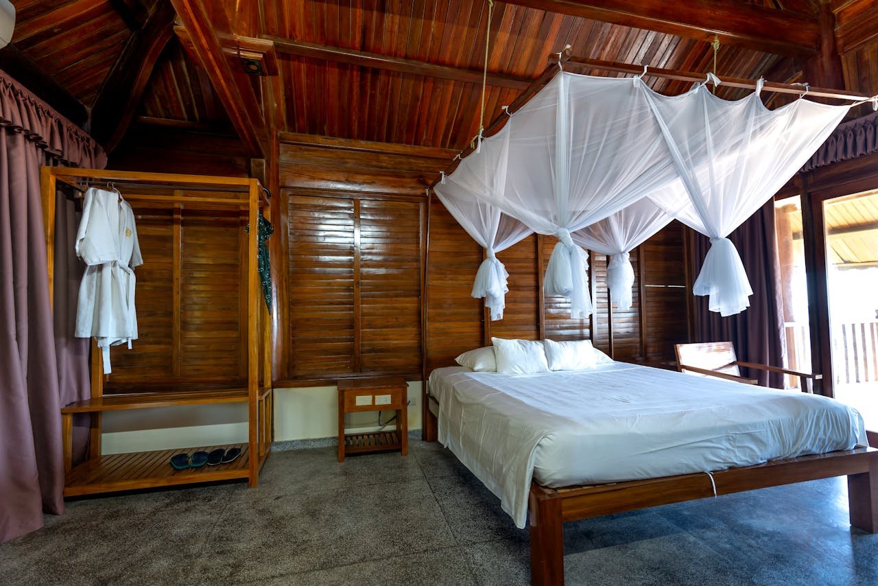 team-01 A serene wooden cabin bedroom featuring a canopy bed and rustic interior decor.